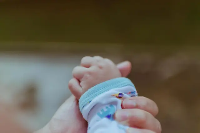 Bir yetişkinin parmağını tutan bebek eli